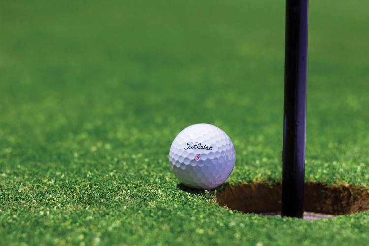 a white golf ball lying next to a golf hole with a pin in it